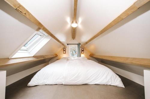une chambre avec un lit blanc dans un grenier dans l'établissement Thalassa Beach Houses, à Zandvoort