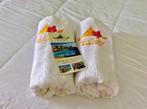 a pair of white socks and a book on a bed at The Orchid Resort & Relax in Maha Sarakham