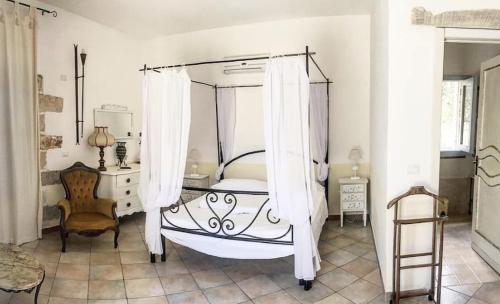 a bedroom with a canopy bed and a chair at Agriturismo Tenuta Sant'Antonio in Cerfignano