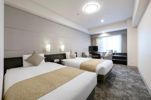 a hotel room with two beds and a desk at Hotel Villa Fontaine Grand Tokyo-Shiodome in Tokyo