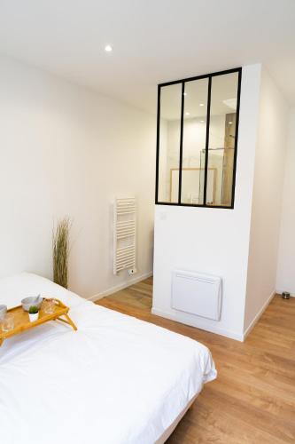 une chambre blanche avec un grand lit et une fenêtre dans l'établissement Appartement confort avec parking privé à Saumur, à Saumur