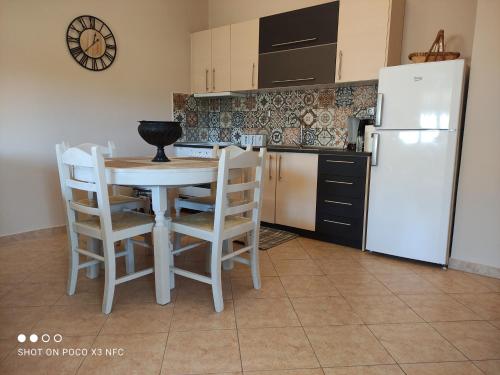 kuchnia ze stołem i krzesłami oraz białą lodówką w obiekcie Eliza Apartment w Lixoúrion