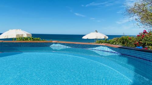 basen z dwoma parasolami i oceanem w obiekcie Beira Mar by Check-in Portugal w Albufeirze