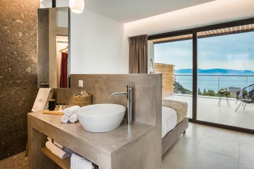 a bathroom with a sink and a large window at Kefalonian Escape Suites in Valeriános