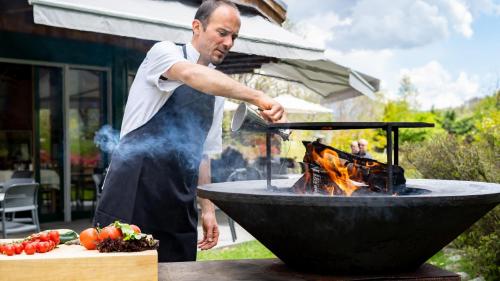 Ein Mann, der über einem Feuer im Grill kocht in der Unterkunft Hotel Il Castagno in Mugena