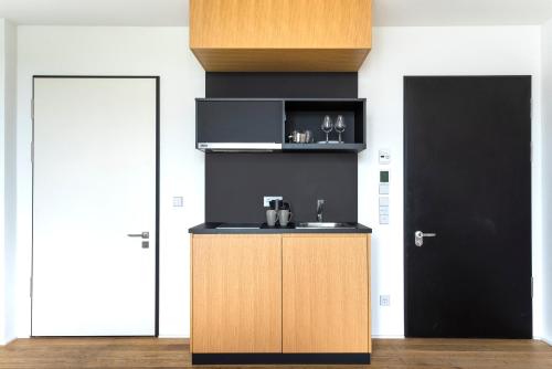 a kitchen with a counter with a sink and a door at Numa Berlin Drift in Berlin
