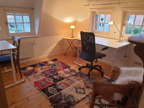 a living room with a desk and chairs and a rug at Villa De Panne in De Panne