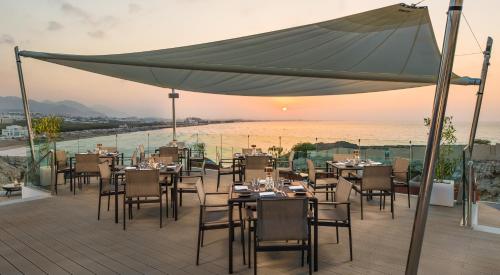 a restaurant with tables and chairs on a deck at Crowne Plaza Muscat, an IHG Hotel in Muscat