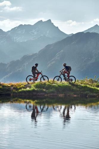 two people riding bikes on a hill next to a body of water at Nonas B&B in Galtür