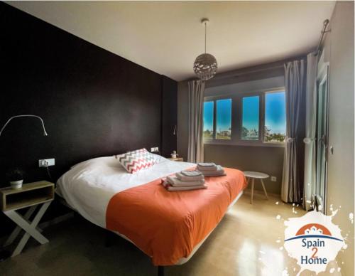 een slaapkamer met een groot bed en een oranje deken bij Atico Las Palmeras Golf by Spain2home in Vélez-Málaga