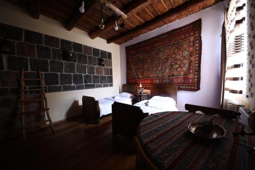 a room with two beds and a rug on the wall at Alashkert Guesthouse ,Ալաշկերտ Հյուրատուն in Gyumri