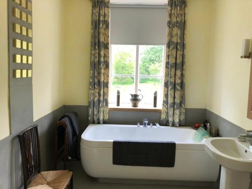 グランサムにあるMarston Hallの浴槽と洗面台と窓のあるバスルーム