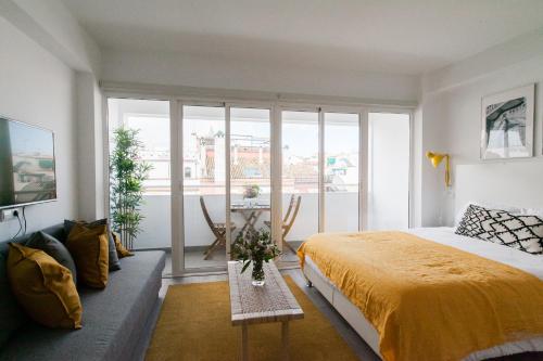 GoToSeville Molviedro Suites في إشبيلية: غرفة نوم بسرير وطاولة مع بطانية صفراء