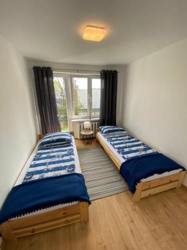 two beds in a room with a window at W Dablju - Apartementy nad morzem in Władysławowo