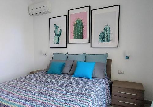 a bedroom with a bed with four pictures on the wall at Dreaming Sorrento Suites in Sorrento