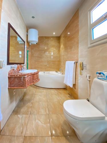 a bathroom with a toilet and a tub and a sink at Best View Pyramids Hotel in Cairo
