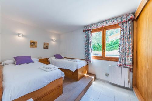 two beds in a room with a window at Sa casa des Padrino in Santa Ponsa