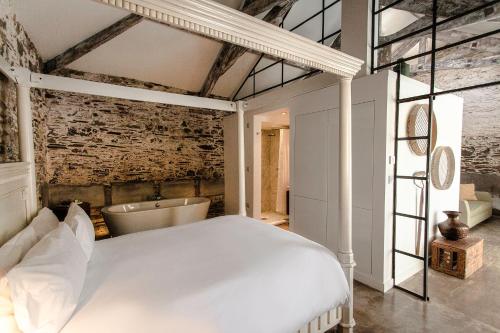 a bedroom with a white bed and a bath tub at ANRÁN at Tidwell Farm in Staverton
