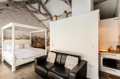 a bedroom with a bed and a black leather couch at ANRÁN at Tidwell Farm in Staverton