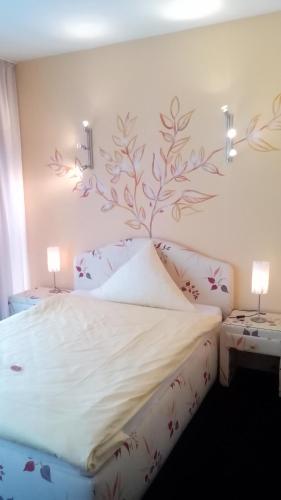 a bedroom with a bed with a tree mural on the wall at Europa Hotel Garni free parking in Fürth