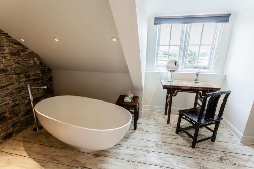 a bathroom with a large bath tub and a table at ANRÁN at Tidwell Farm in Staverton