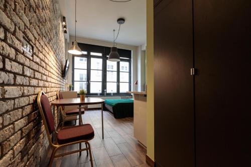 Cette chambre dispose d'un mur en briques, d'une table et de chaises. dans l'établissement Golden Apartments Wroclaw&K24, à Wrocław