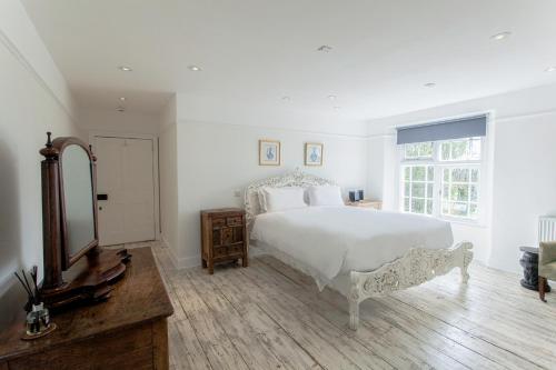 a bedroom with a white bed and a mirror at ANRÁN at Tidwell Farm in Staverton