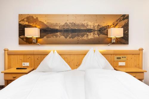 a bedroom with a white bed with two lamps at Hotel Pongauerhof in Flachau