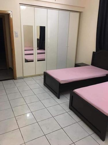 two beds in a room with pink sheets at بناية بلازا٢ in Dubai