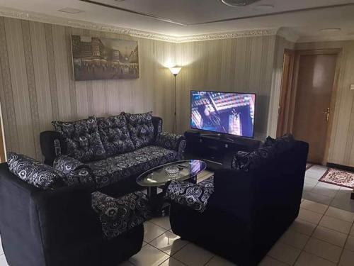 un soggiorno con divano nero e TV di بناية بلازا٢ a Dubai