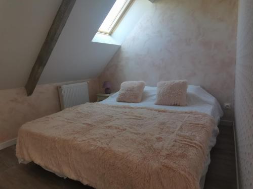 een slaapkamer met een bed met 2 kussens erop bij L'atelier les hortensias in Marquise