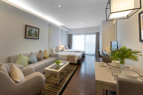 ein Wohnzimmer mit einem Sofa und einem Bett in der Unterkunft Cape Racha Hotel in Si Racha