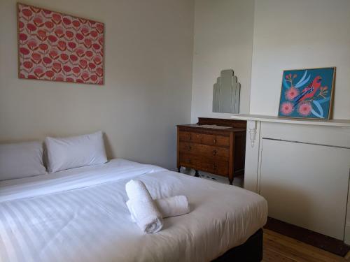ein Schlafzimmer mit einem Bett und einer Kommode mit Handtüchern darauf in der Unterkunft Cute cottage walking distance to CBD in Wagga Wagga
