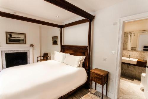 a bedroom with a large white bed and a fireplace at ANRÁN at Tidwell Farm in Staverton