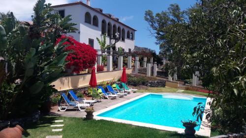 a swimming pool in front of a building with chairs and umbrellas at Romantic Studio in Funchal