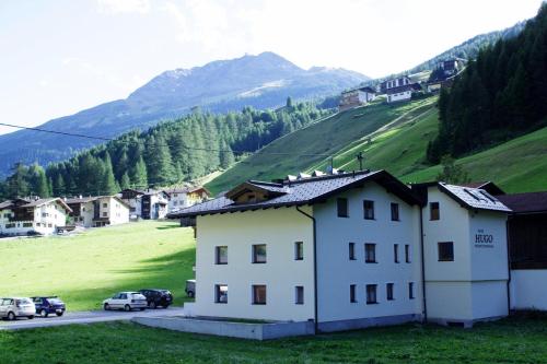 a white house on a hill with a green field at Haus Hugo in Sölden