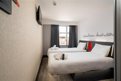 um quarto de hotel com duas camas e uma janela em easyHotel Oxford em Oxford