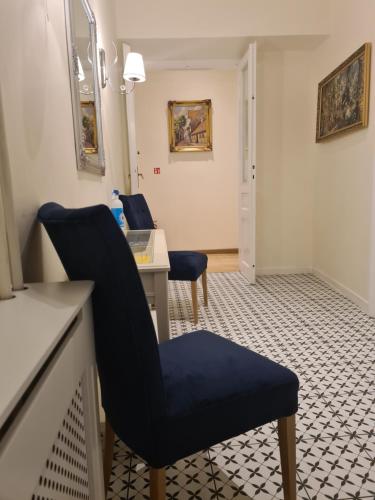 a waiting room with a blue chair and a desk at Amber Hostel in Kraków