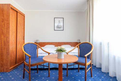 a room with a table and two chairs and a bed at Hotel Marina in Międzyzdroje