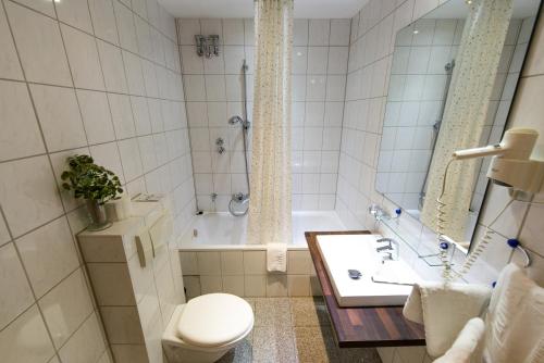 a bathroom with a tub and a toilet and a sink at Löwen Hotel in Offenbach