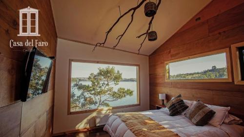 ein Schlafzimmer mit einem Bett und zwei großen Fenstern in der Unterkunft Casa del Faro Chiloé in Castro