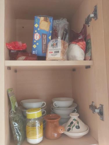 a shelf with dishes and other items in a pantry at Ideal Appart Ain Zaghouan Tunis in El Aouina