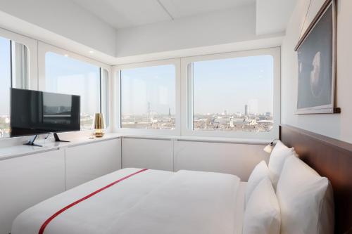 biały pokój z łóżkiem i telewizorem w obiekcie Ruby Luna Hotel Dusseldorf w mieście Düsseldorf