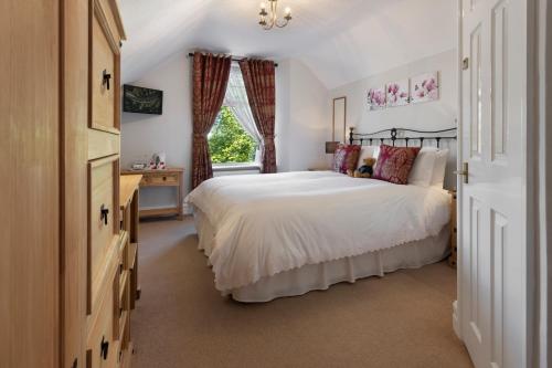 Un dormitorio con una gran cama blanca y una ventana en Beechwood en Bowness-on-Windermere