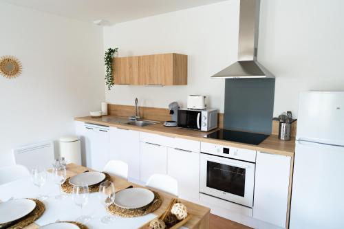 uma cozinha com armários brancos e uma mesa com cadeiras em Appartement cosy dans une longère de caractère em Saumur