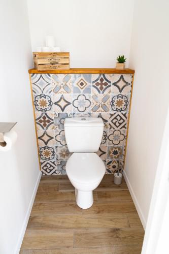 a bathroom with a toilet and a tiled wall at Appartement cosy avec parking privé à Saumur in Saumur