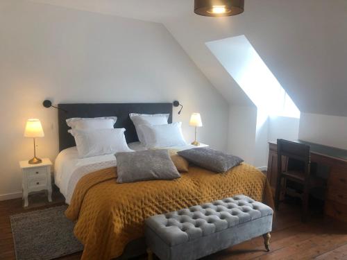 a bedroom with a large bed and a bench in it at L'Otentik Restaurant Chambres d'Hôtes in Rosporden