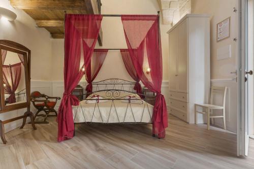 a bedroom with a canopy bed with red curtains at Salento Ada's House in Melendugno