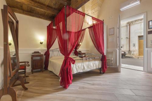 a bedroom with a canopy bed with red curtains at Salento Ada's House in Melendugno