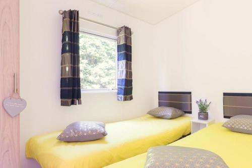 two beds in a room with yellow sheets and a window at Twente 4 persons in Rijssen